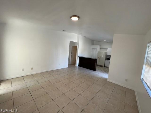 Spare room featuring light tile patterned floors, vaulted ceiling, and recessed lighting