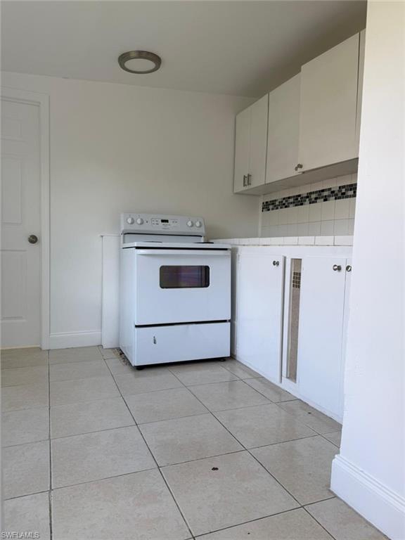 Kitchen featuring white cabinets, tile countertops, white electric range, and light tile patterned floors