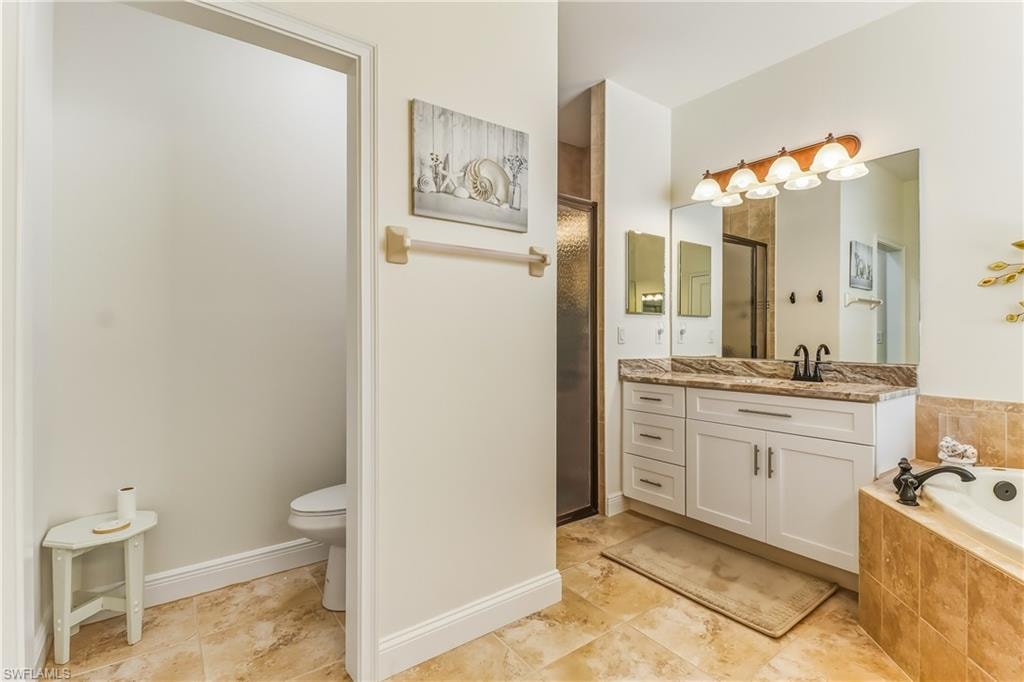 Bathroom with vanity, a bath, and a stall shower