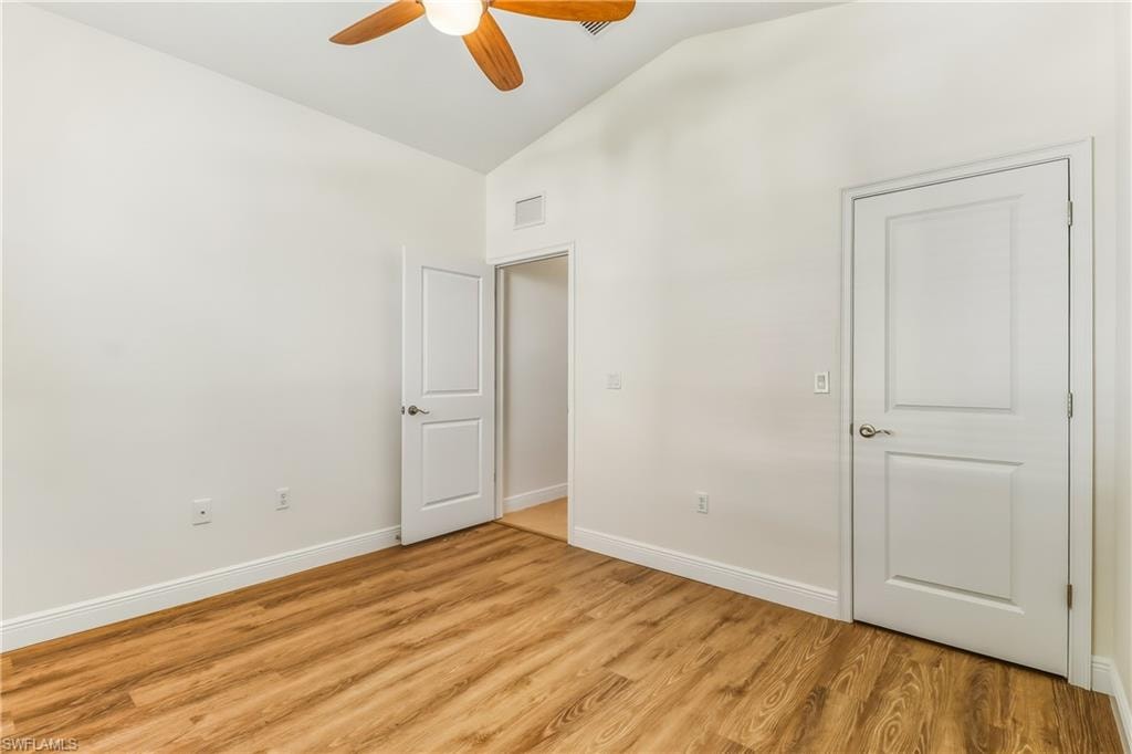Unfurnished bedroom featuring lofted ceiling, light wood-style floors, and a ceiling fan