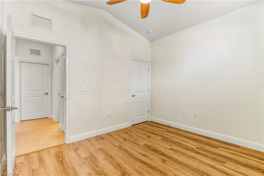 Unfurnished bedroom featuring light wood-style flooring, vaulted ceiling, and a ceiling fan