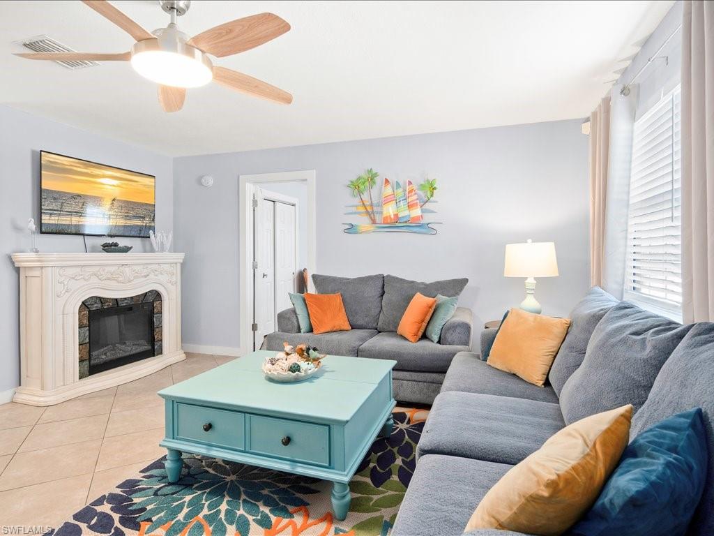 Tiled living room featuring a high end fireplace and ceiling fan