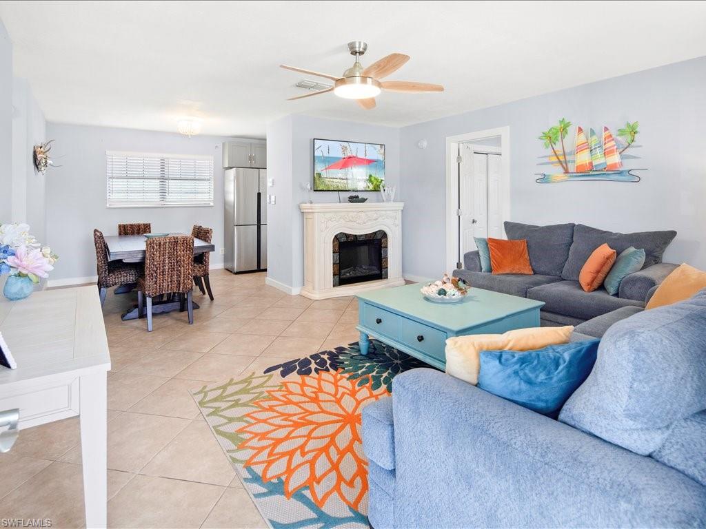 Living area with light tile patterned floors, a premium fireplace, and ceiling fan