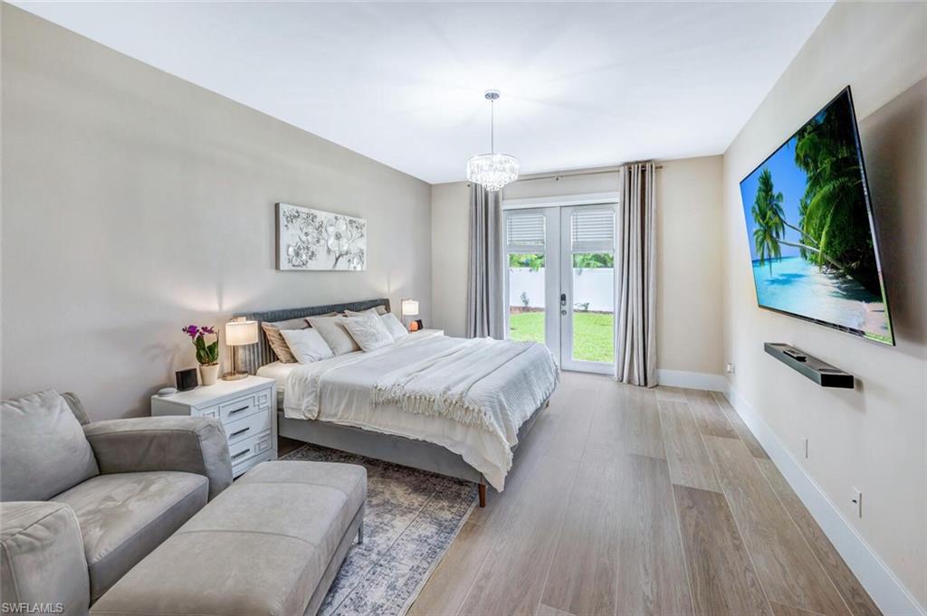 Bedroom featuring wood finished floors, french doors, a chandelier, and access to exterior