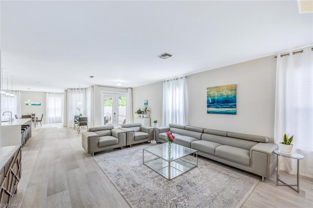 Living room with light wood finished floors, french doors, and healthy amount of natural light