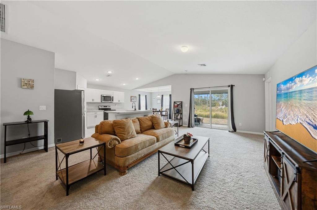 Living area with light carpet and lofted ceiling