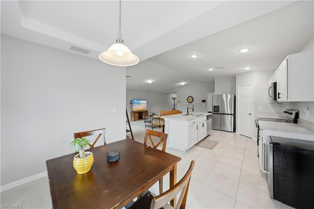 Dining space with vaulted ceiling, light tile patterned floors, and recessed lighting
