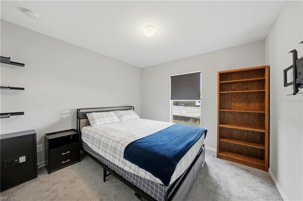 Bedroom with light colored carpet and baseboards