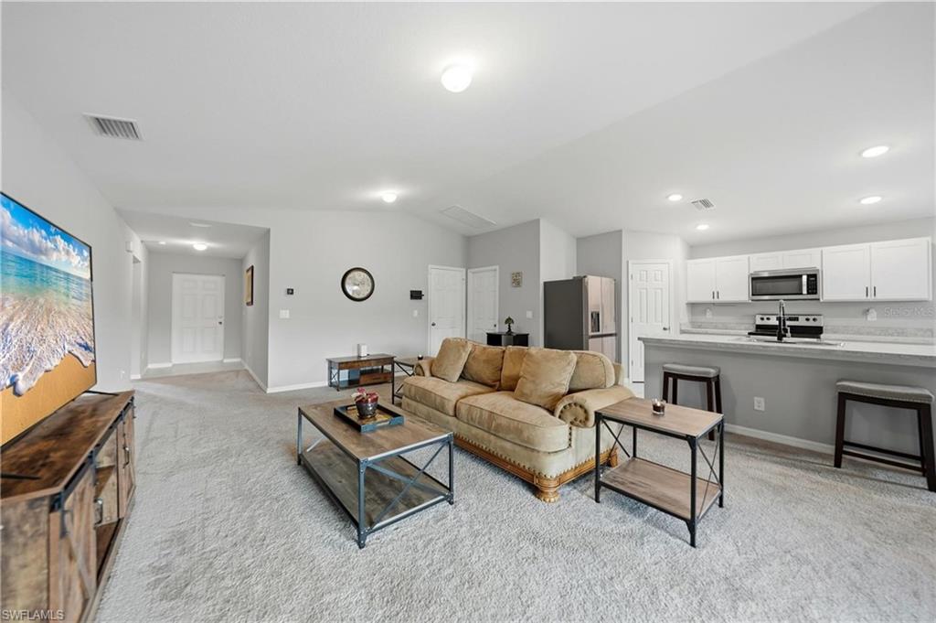 Living area featuring light colored carpet, lofted ceiling, and recessed lighting