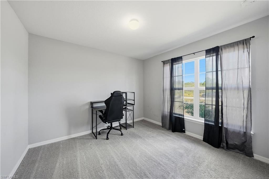 Office space with baseboards and light carpet