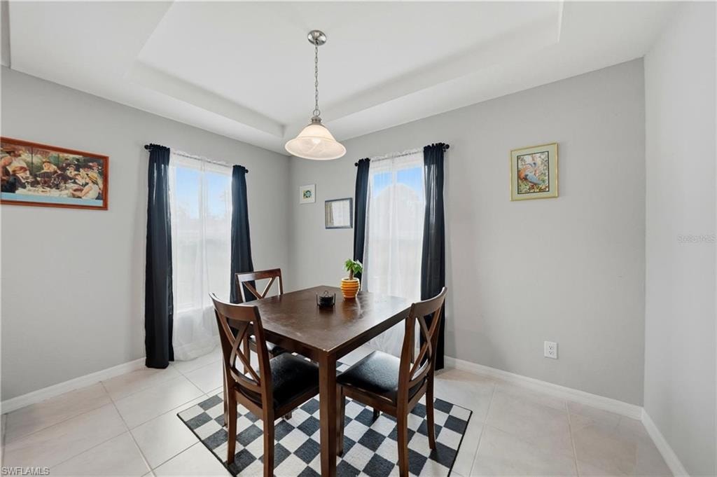 Dining room featuring a raised ceiling and light tile patterned flooring