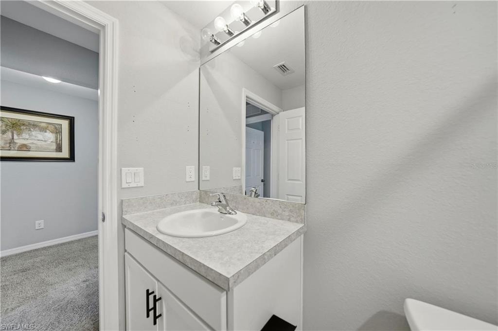 Half bath featuring vanity, carpet floors, and a textured wall