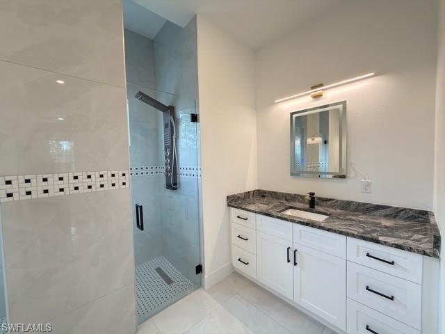 Full bathroom with a shower stall, vanity, and light tile patterned floors