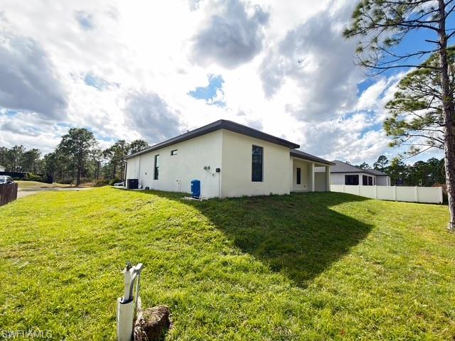 Rear view of house with a yard, stucco siding, and a patio
