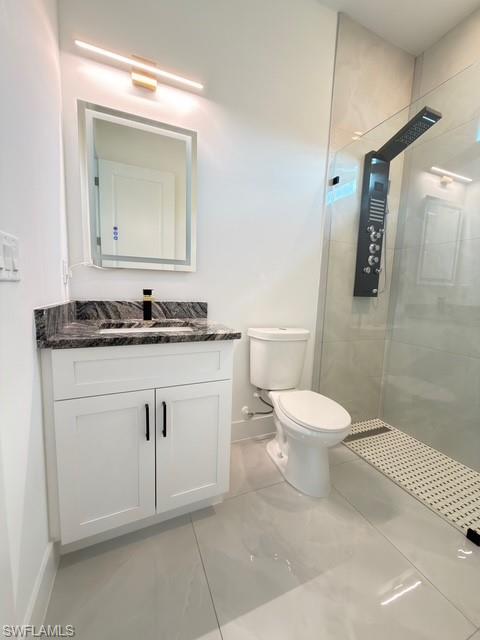 Full bathroom featuring a stall shower, vanity, and light tile patterned floors