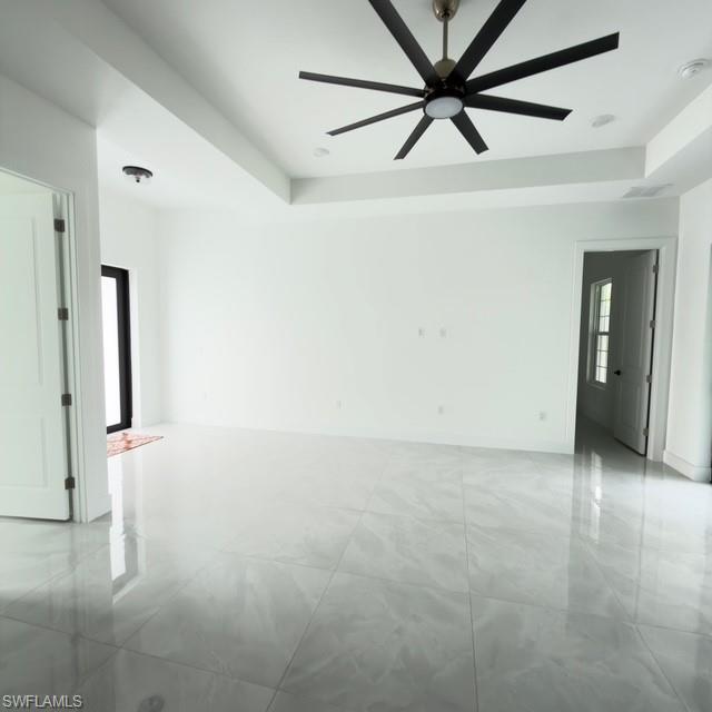 Unfurnished living room with a raised ceiling, ceiling fan, recessed lighting, and french doors