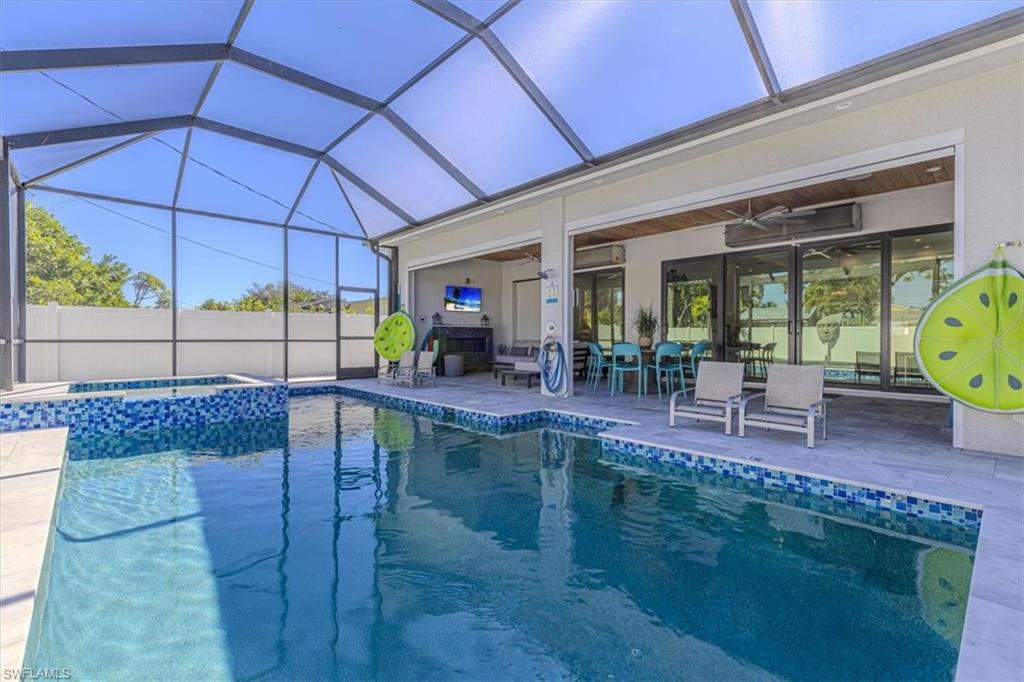 View of pool with glass enclosure, a sunroom, a patio area, and a pool with connected hot tub