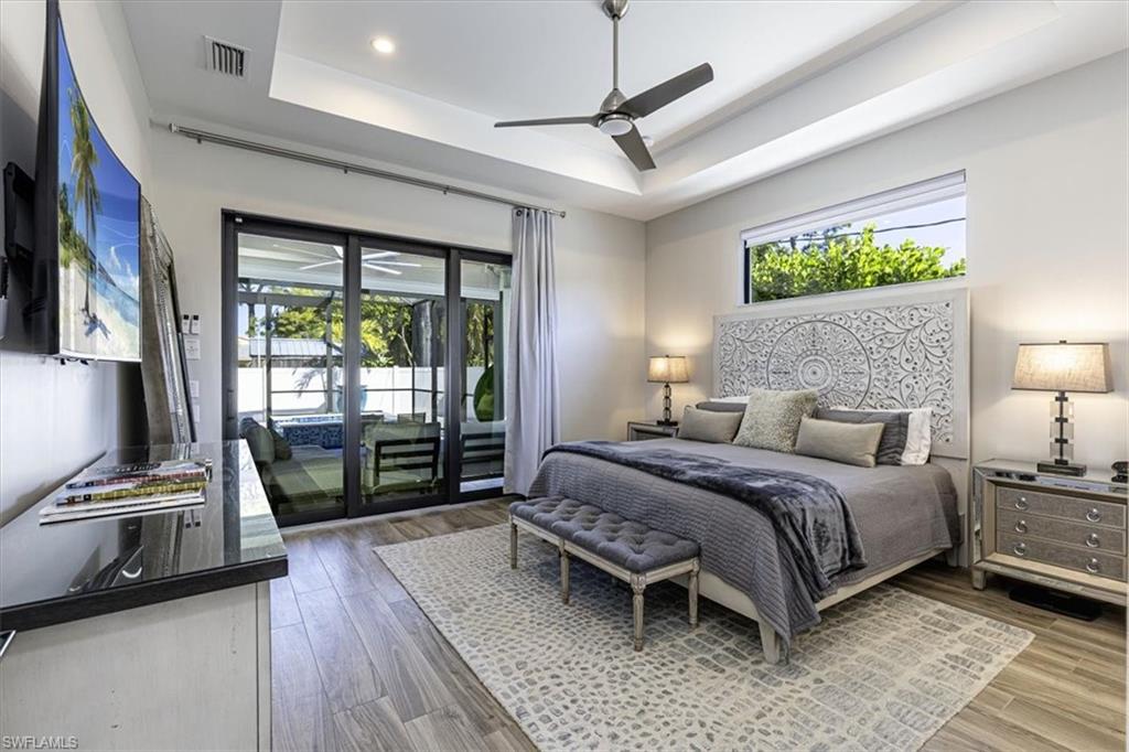 Bedroom featuring access to outside, multiple windows, a ceiling fan, and wood finished floors