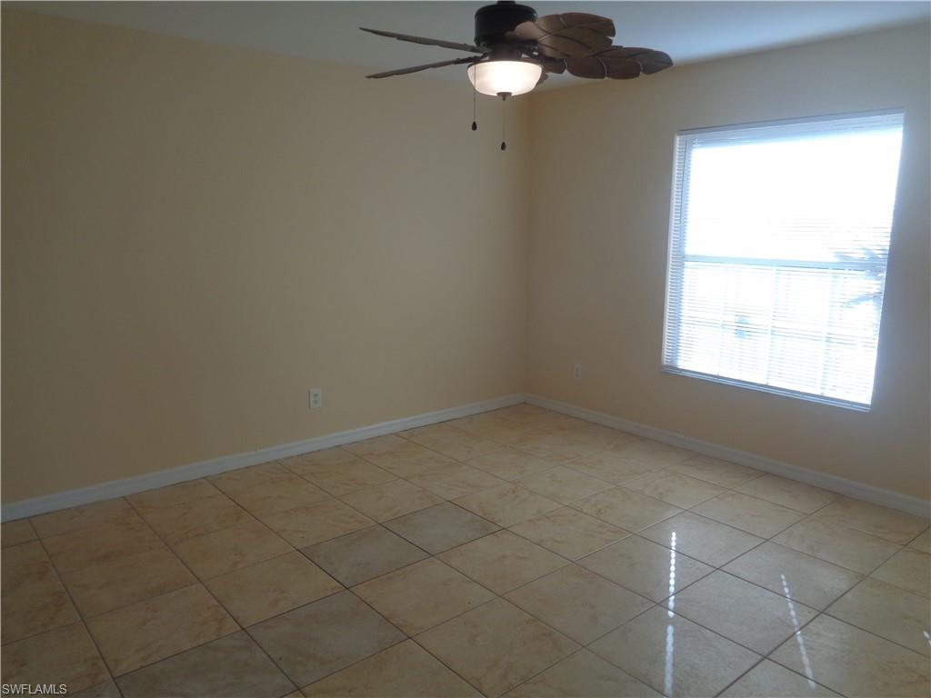 Master bedroom with light tile patterned floors and ceiling fan