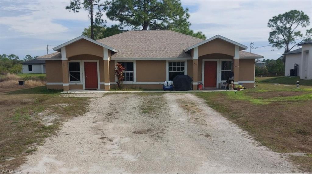 Single story duplex with stucco siding, roof with shingles and driveway