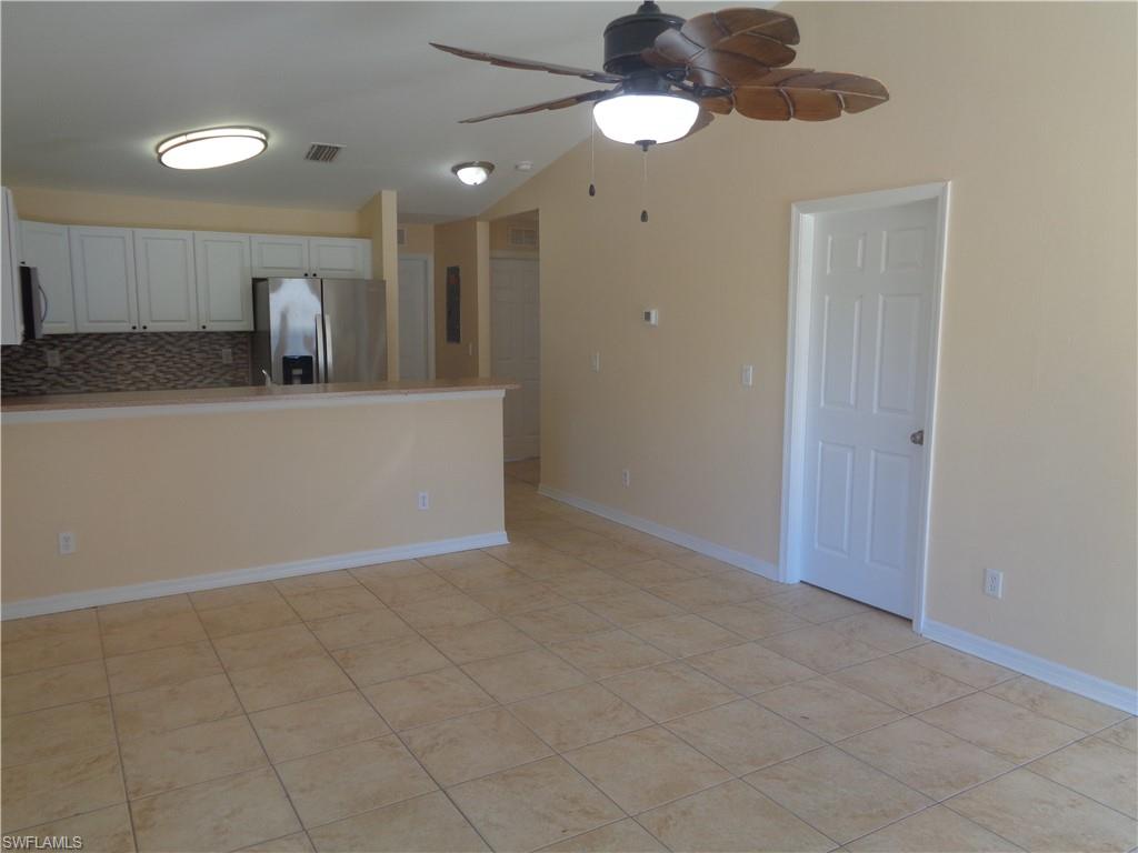Family room and kitchen featuring vaulted ceiling, appliances with stainless steel appliances, white cabinetry, fan ceiling and light tile patterned floors
