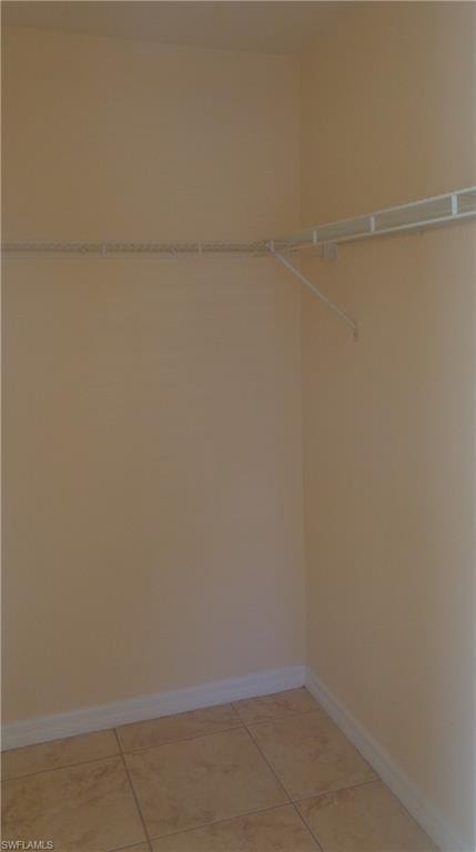 Master bedroom's spacious walk-in closet featuring light tile patterned flooring