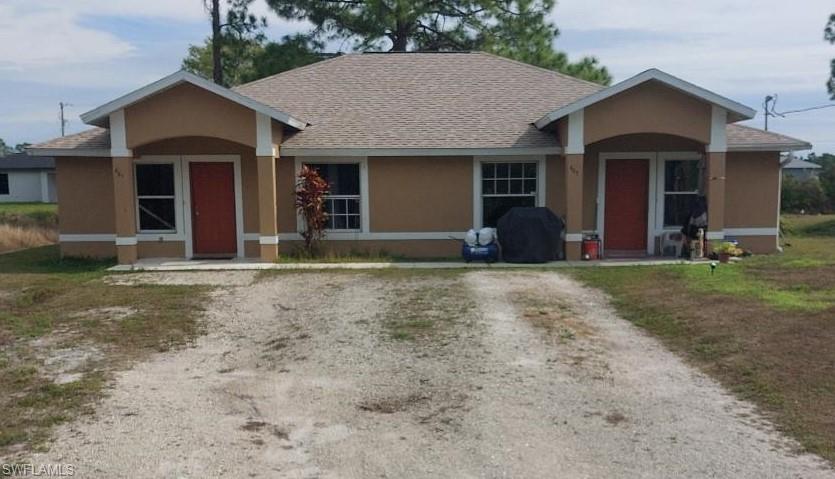 Single story duplex with stucco siding, roof with shingles and driveway