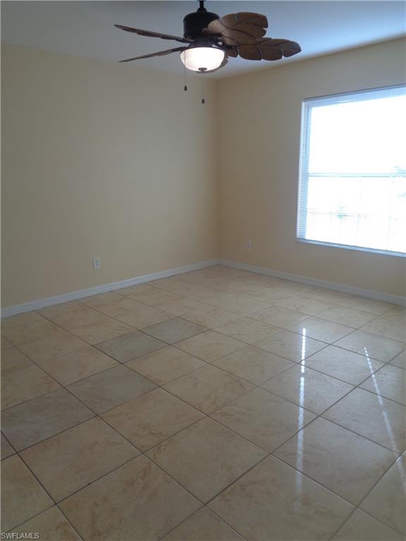 Master bedroom with light tile patterned floors and ceiling fan