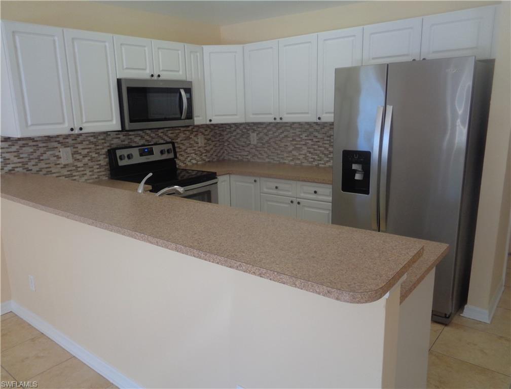 Kitchen featuring light tile patterned flooring, appliances with stainless steel appliances, and decorative backsplash