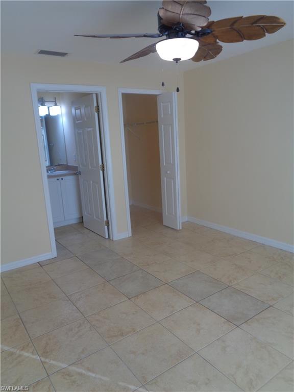Master bedroom with a walk in closet, a ceiling fan, and light tile patterned floors