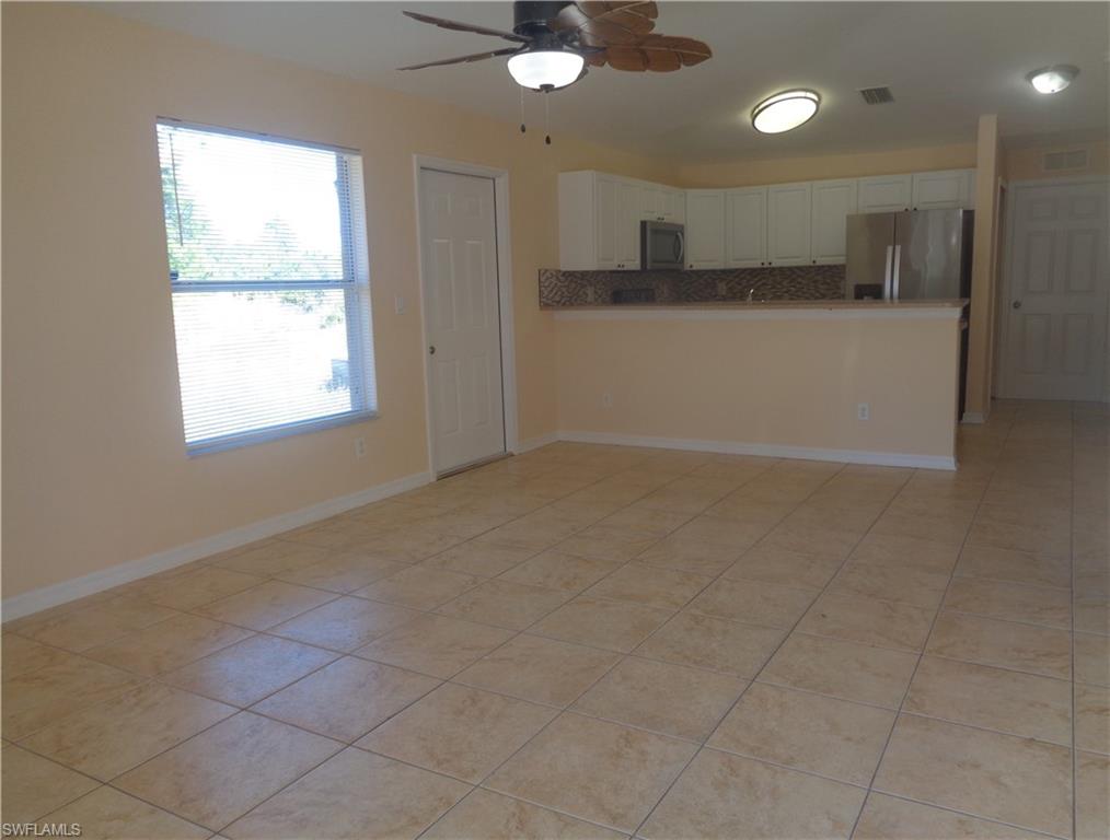 Family room and kitchen with white cabinets, stainless steel appliances, and light tile patterned flooring