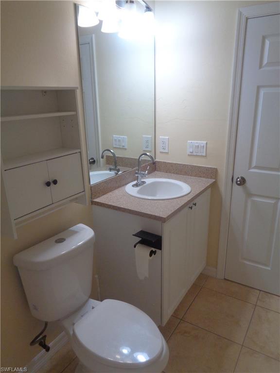 Guest bathroom with vanity, toilet and light tile patterned floors