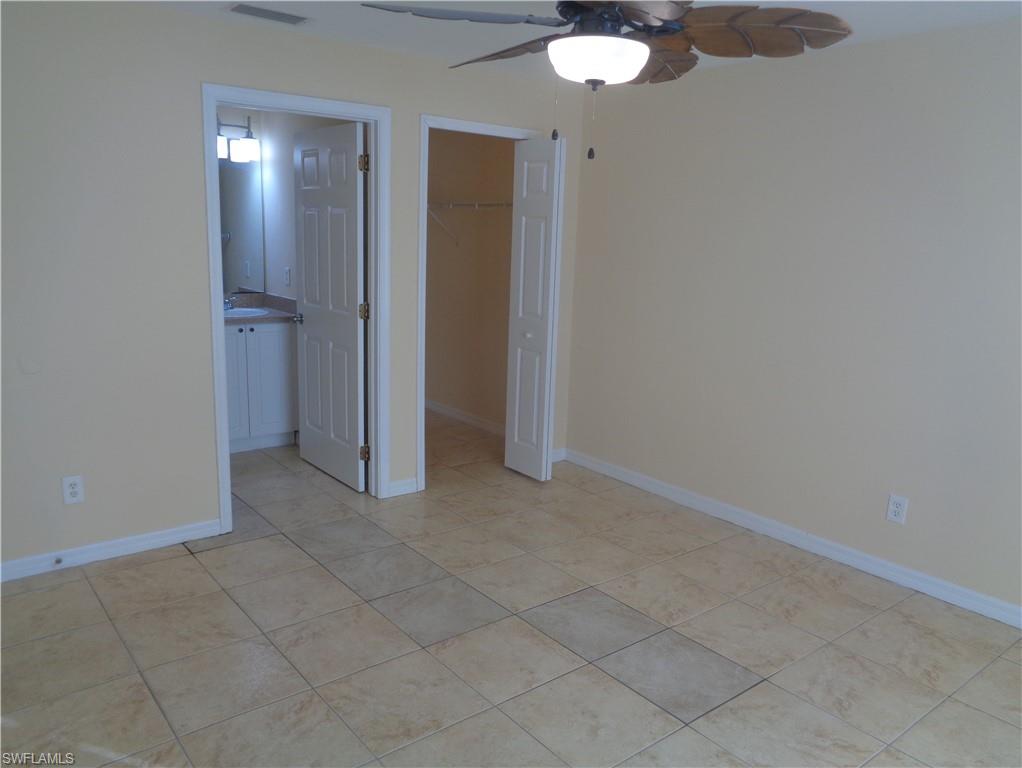 Master bedroom with a walk in closet, a ceiling fan, and light tile patterned floors