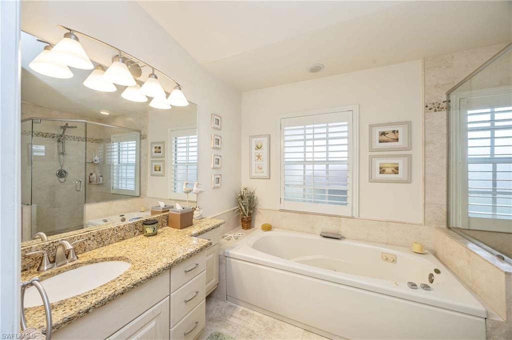 Bathroom featuring a bath, vanity, and a shower stall