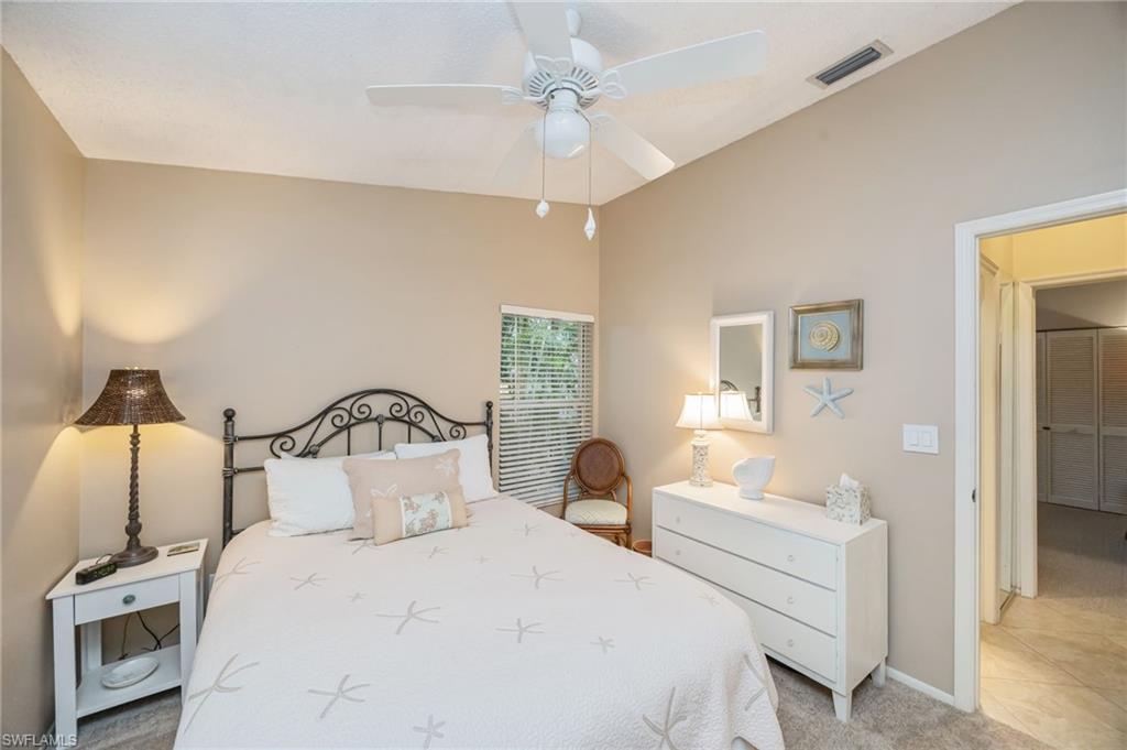 Bedroom with queen sized bed, light colored carpet and a ceiling fan