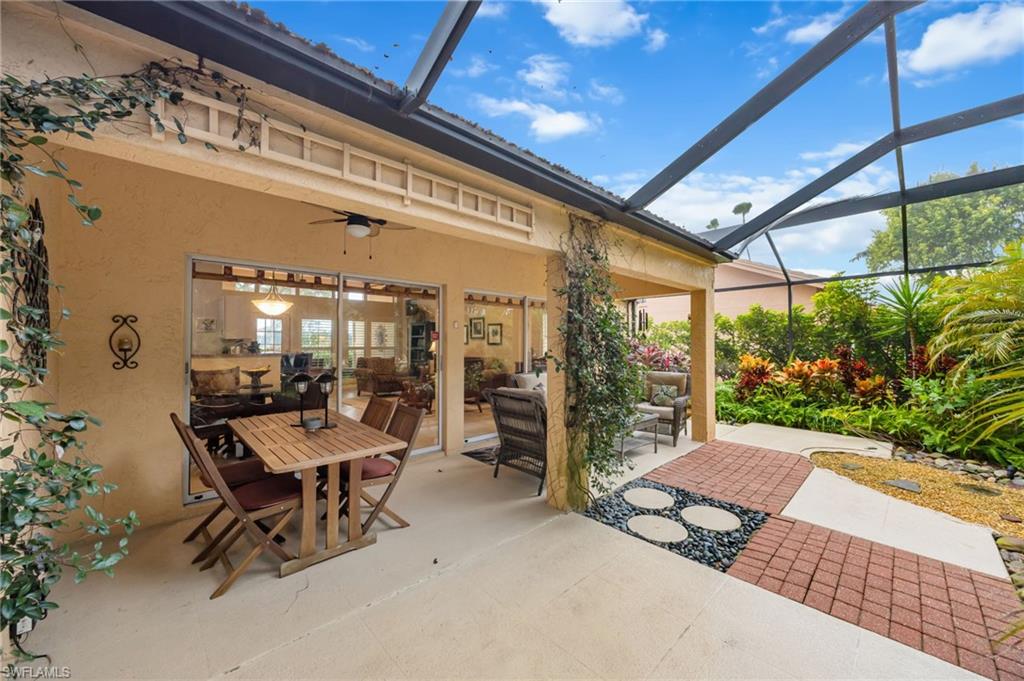 View of screened in lanai, featuring an outdoor living space, a ceiling fan, outdoor dining space, and mature landscaping