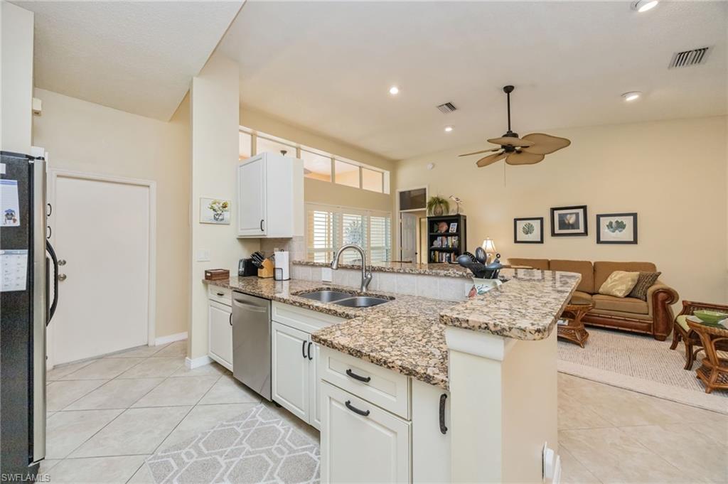 Kitchen featuring a peninsula, light stone countertops, appliances with stainless steel finishes, white cabinetry, and recessed lighting