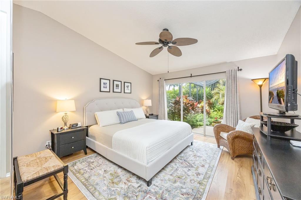 Bedroom featuring king sized bed, light wood-style floors, lofted ceiling, access to exterior, and ceiling fan
