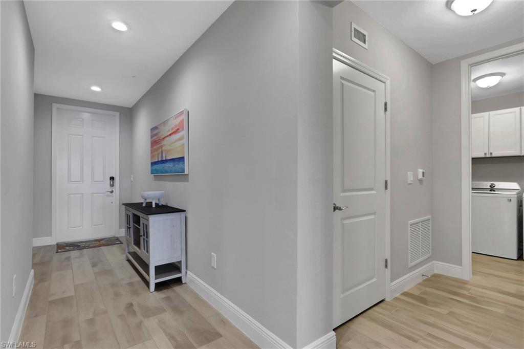 Hallway with washer / clothes dryer, light wood-style floors, and recessed lighting