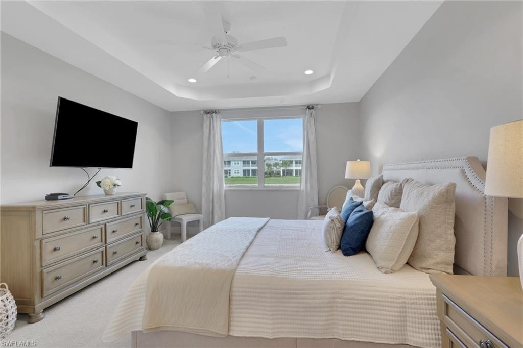 Bedroom with recessed lighting, ceiling fan, light colored carpet, and a raised ceiling