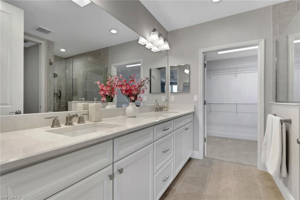 Full bathroom with a shower stall, double vanity, a spacious closet, light tile patterned flooring, and recessed lighting