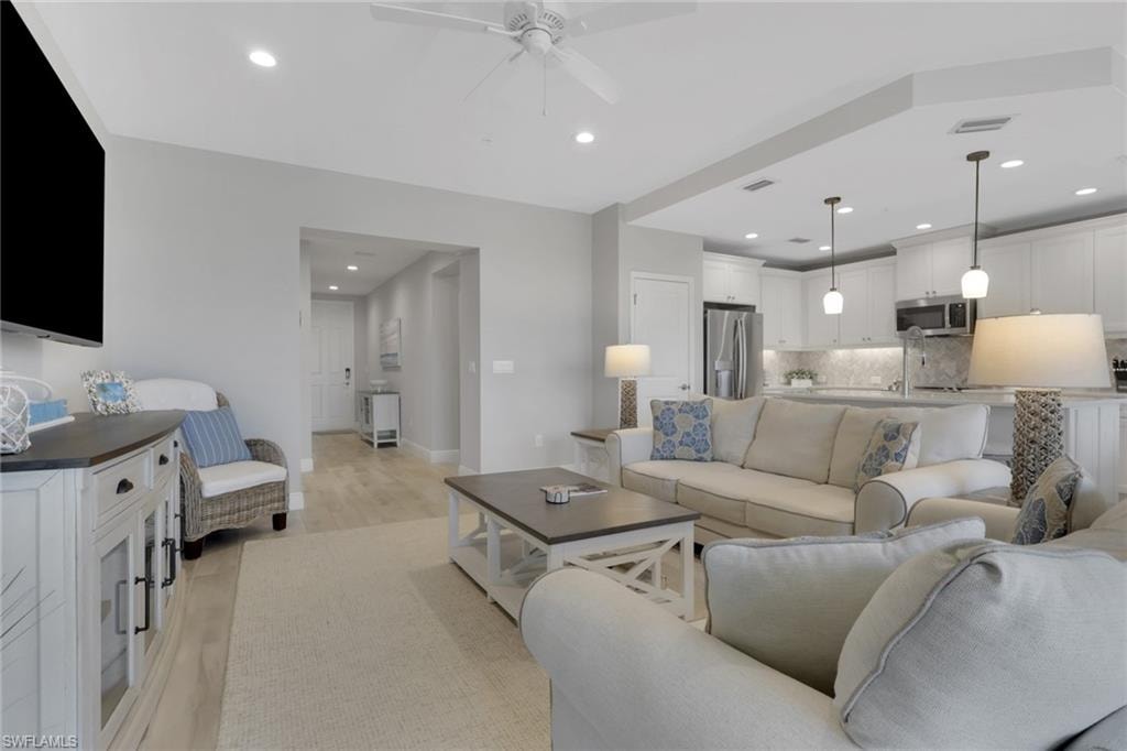 Living room with recessed lighting, ceiling fan, and light wood-type flooring
