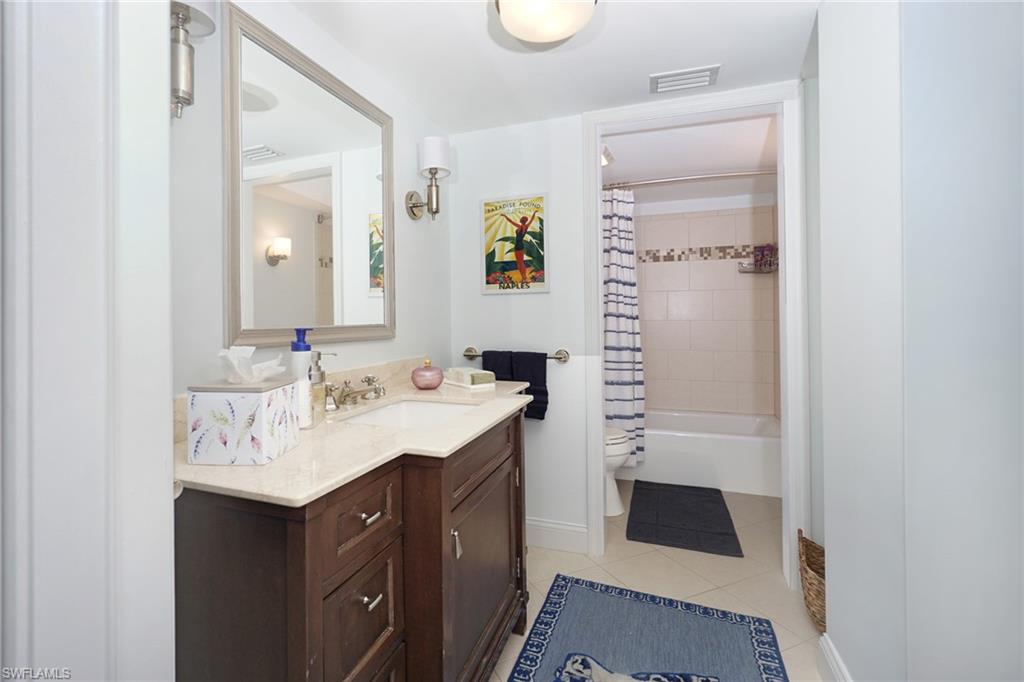 Bathroom featuring vanity, shower / bathtub combination with curtain, and light tile patterned floors