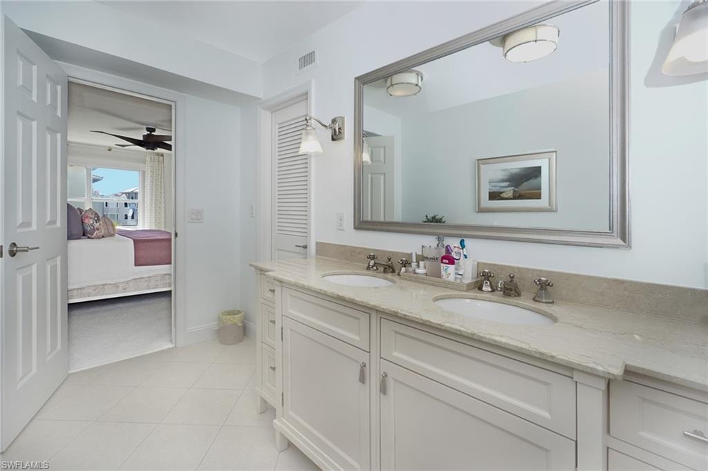 Bathroom with double vanity, ensuite bath, ceiling fan, and light tile patterned floors