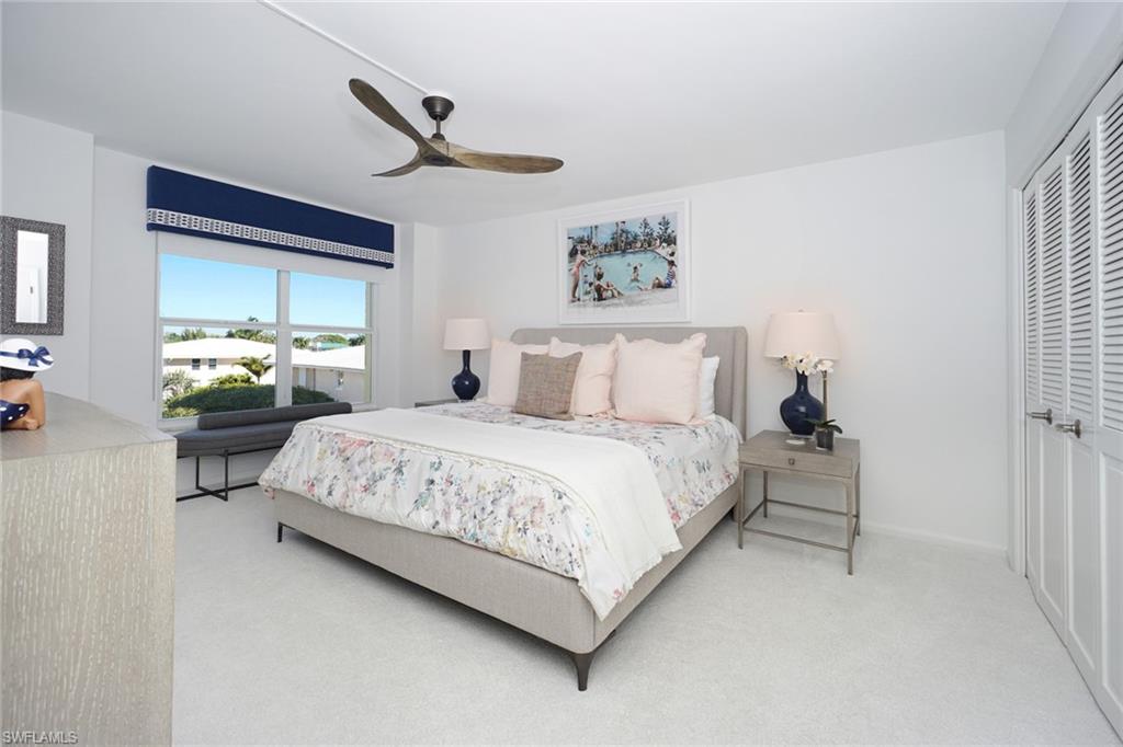 Carpeted bedroom with ceiling fan and a closet