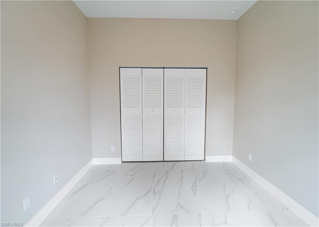 Unfurnished bedroom featuring a closet and light marble finish floors