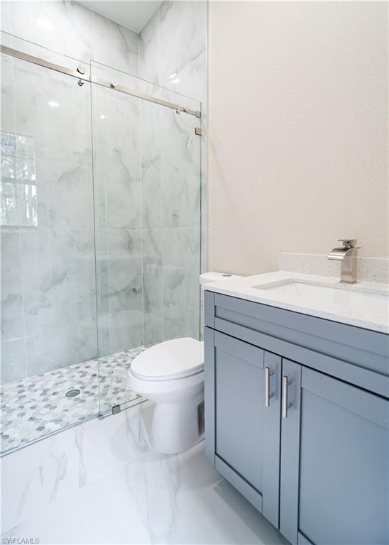 Full bath featuring a marble finish shower and vanity