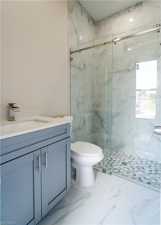 Bathroom featuring a marble finish shower and vanity