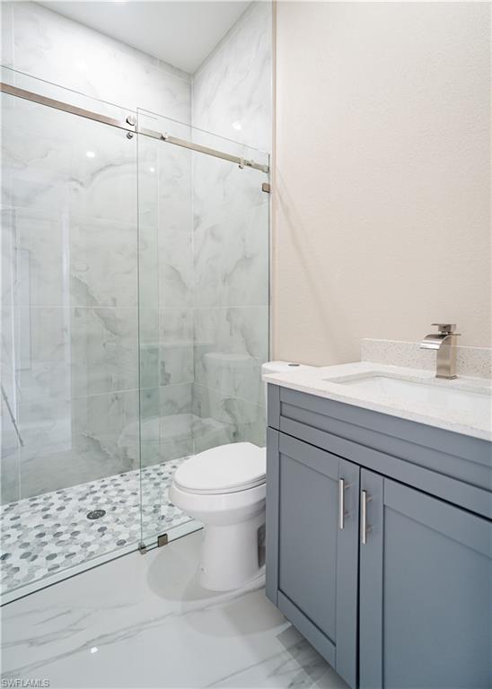 Full bath featuring a marble finish shower and vanity