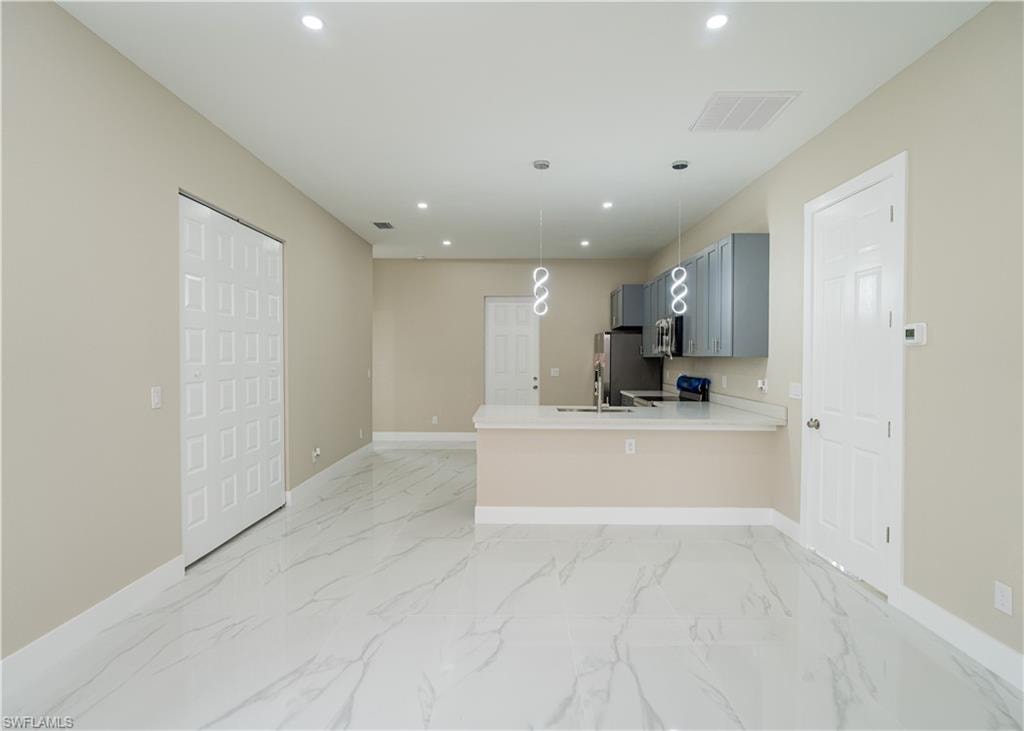 Kitchen featuring a peninsula, electric range oven, hanging light fixtures, recessed lighting, and light stone countertops